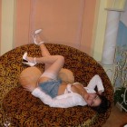 Junge sexy Frau in Minirock und weißen Nylons räkelt sich auf einem Sofa